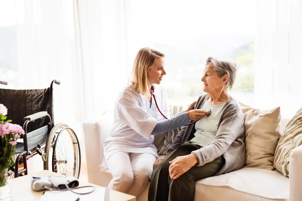 An adult daughter sitting with her elderly parent at home during a doctor visit